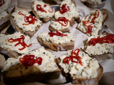 Brotscheiben mit hellem Kräuteraufstrich und roten Paprikastreifen