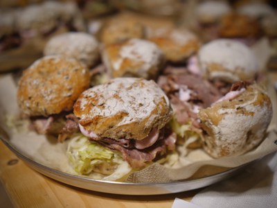 Kleine bemehlte Brötchen mit Fleisch und Krautsalat auf einer Metallplatte