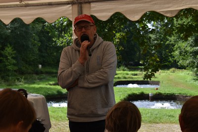 Tag der Fische 2026, Gert Dirkwinkel Leiter der Fischkommission Slow Food Deutschland © Slow Food Deutschland Mann mit Slow-Food-T-Shirt hält Mikrofon unter einem Zeltdach
