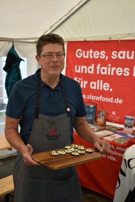 Thomas Rinke-CV Südlicher Teutoburger Wald- servierte Häppchen © Slow Food Deutschland Mann mit Slow-Food-Schürze hält ein Brett mit Häppchen
