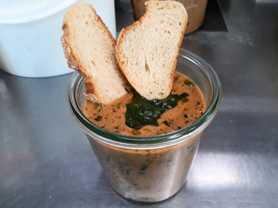 Gemüseeintopf auf Basis der Pilz-Bolognese Eintopf in einem Weckglas mit Kräuterpesto, zwei Scheiben Brot stecken darin