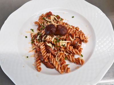Pilz-Bolognese mit Pasta, Kräutern und Käse (c) Jan-Hendrik Parker Fusilli mit Pilz-Bolognese, geriebenem Käse und Schnittlauch, garniert mit zwei ganzen Shiitake-Pilzen, auf einem weißen Teller