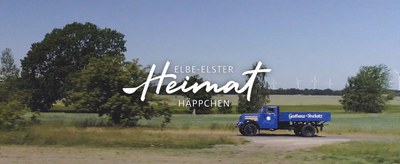 Blauer Oldtimer-Lieferwagen des Gasthaus Stuckatz fährt durch die Lausitzer Landschaft, Schriftzug Elbe-Elster Heimathäppchen 