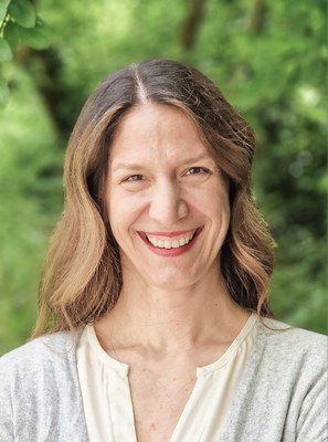 Porträt Nora Brüggemann Weibliche Person im Porträtfoto lächelnd mit grüner Natur im Hintergrund